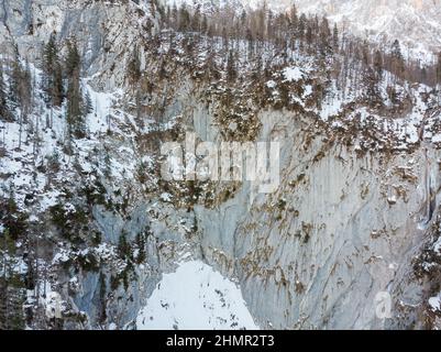 Vue aérienne spectaculaire de la chute d'eau gelée tombant sur le rebord rocheux en hiver. Banque D'Images