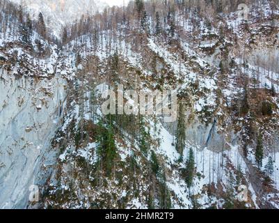 Vue aérienne spectaculaire de la chute d'eau gelée tombant sur le rebord rocheux en hiver. Banque D'Images