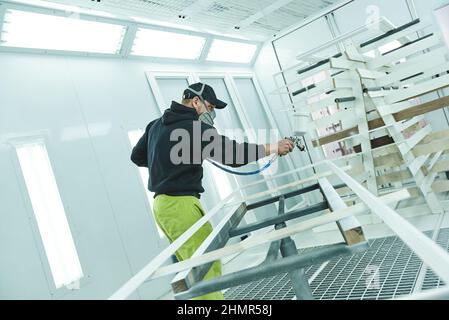 Faites-le correctement. Homme dans masque respiratoire peinture de planches en bois à l'atelier Banque D'Images