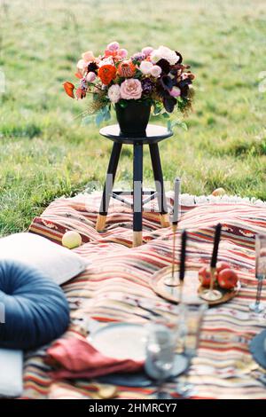 Bouquet de mariage dans un vase est placé sur un tabouret sur un couvre-lit coloré Banque D'Images