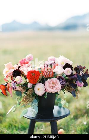 Le bouquet de mariage dans un vase est placé sur un tabouret sur une pelouse verte. Gros plan Banque D'Images