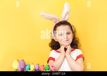 Portrait de petite fille adorable avec sourire heureux, forme le coeur avec les deux mains, exprime l'amour à vous, porte des oreilles moelleuses, prépare pour le ho important Banque D'Images