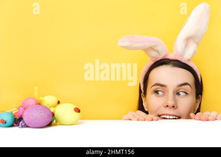 Joyeuses pâques ! Charmante joyeuse jeune caucasienne commence à chasser pour les oeufs de Pâques, porte des oreilles moelleuses, pose sur fond jaune dans St Banque D'Images
