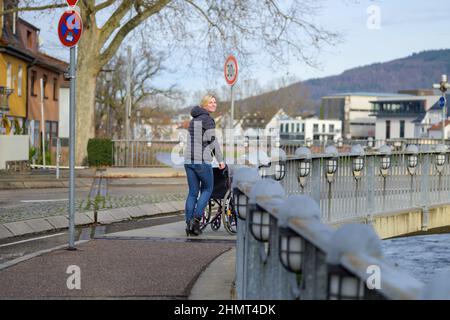 Une jeune femme pousse un fauteuil roulant vide dans la ville tout en regardant la caméra Banque D'Images