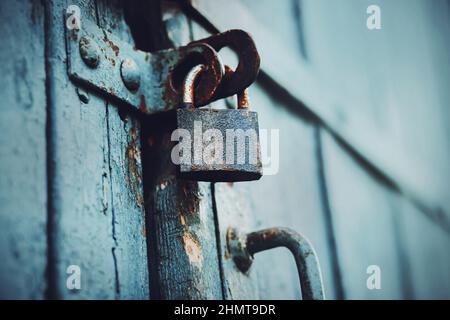 La grande porte en bois bleu est fermée par un vieux cadenas rouillé. Outils et articles ménagers. Le secret est caché derrière les portes. Fermé. Banque D'Images