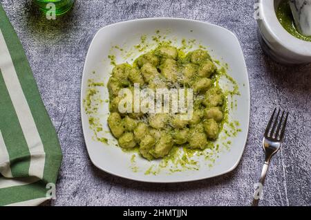 Gnocchi de pomme de terre assaisonné de pesto alla genovese. Les gnocchi de pomme de terre sont faits maison avec des pommes de terre biologiques. Une cuisine italienne traditionnelle typique, saine a Banque D'Images