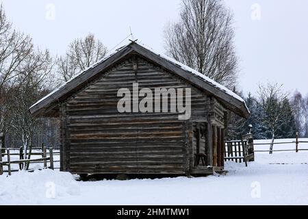 Paysage russe d'hiver. Une ancienne hutte en bois, une maison en bois avec un toit de chaume. Village russe abandonné couvert de neige. Maison en rondins avec grange. Banque D'Images