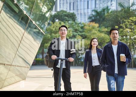 trois jeunes adultes asiatiques deux hommes et une femme marchant dans la rue heureux et souriants Banque D'Images