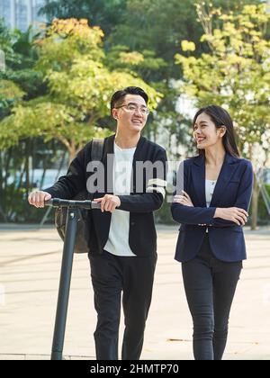 jeune asiatique homme et femme marchant bavardant dans la rue heureux et souriant Banque D'Images