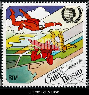 GUINÉE-BISSAU - VERS 1985 : un timbre imprimé en Guinée-Bissau montre le parachutisme, année internationale de la jeunesse, vers 1985 Banque D'Images