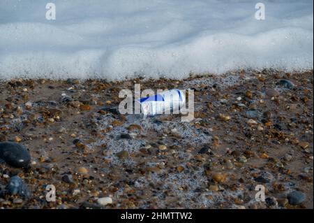 Jeter la boisson énergétique usagée lavée sur une plage de sable de Norfolk Banque D'Images