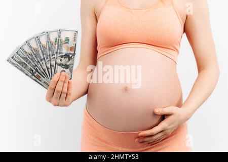 la femme enceinte tient des billets dans ses mains sur un fond blanc. Dépenses monétaires pour la grossesse et l'accouchement. Grossesse et maternité de substitution - p Banque D'Images