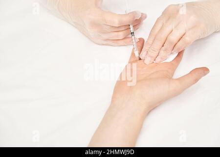 Injection de paume au spa.Médecin mains dans des gants.Gros plan.Joli patient Banque D'Images