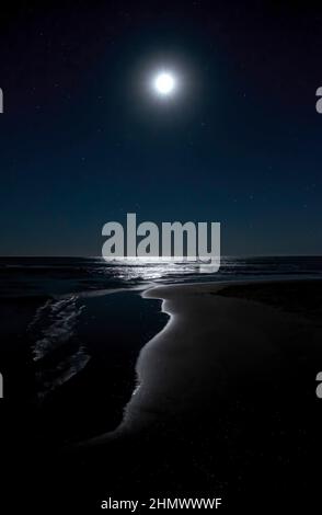 Image nocturne d'une plage avec la lune dans le ciel étoilé se reflétant sur l'eau de la mer, peinture d'une grotte de lumière, Isla Canela, Huelva Espagne, v Banque D'Images