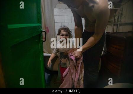 Gornyak, Ukraine. 9th févr. 2022. Igor nettoie les mains de Lera, 3 ans, dans la salle de bains unique des appartements le 9 février 2022. Igor et Eugenia, les parents de 5 enfants âgés de moins de 8 ans, vivent à environ 20 km des lignes de front de Donetsk à Gornyak, en Ukraine. La famille lutte pour trouver suffisamment de travail pour la nourriture et les factures et reste préoccupée par la mobilisation des forces militaires russes à la frontière ukrainienne. (Credit image: © Michaal Nigro/Pacific Press via ZUMA Press Wire) Banque D'Images