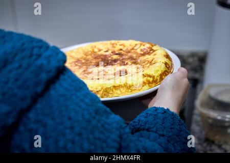 femme méconnaissable portant une omelette à la pomme de terre espagnole. Banque D'Images