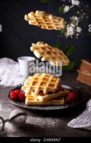 Gaufres faites maison flottant avec sucre glace et fruits. Banque D'Images