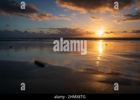 Coucher de soleil avec nuages et réflexions illuminés, à Sandy Gap, plage de Walney, île de Walney, barrow in furness, Cumbria, Royaume-Uni, le 4th février 2022 Banque D'Images