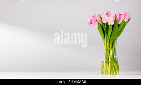 Tulipes roses dans un vase sur une table blanche Banque D'Images