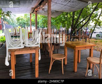 La terrasse en bois d'été du café est fermée, il n'y a pas de personnes, les chaises sont renfermées, les arbres verts sont tout autour. Banque D'Images