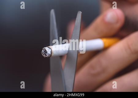 Couper la cigarette avec des ciseaux. Arrêter de fumer, cesser de fumer ou ne pas fumer concept. Refuser le tabac et cesser la mauvaise habitude Banque D'Images