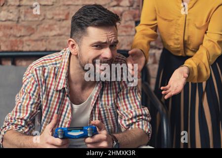 L'homme d'âge moyen européen ne veut pas être interrompu par son parent tout en se relaxant avec son nouveau jeu d'ordinateur. Photo de haute qualité Banque D'Images