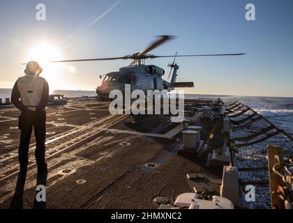 OCÉAN ATLANTIQUE EST (FÉV 10, 2022) le Mate 2nd de Boatswain classe Omaro Luke observe comme un hélicoptère MH-60R Seahawk, attaché à HSM 79, s’arrête à bord du destroyer à missiles guidés de la classe Arleigh Burke USS Roosevelt (DDG 80), 10 février 2022. Roosevelt, déployé vers l'avant à Rota, en Espagne, est en troisième patrouille dans la zone de la Sixième flotte des États-Unis pour soutenir les alliés et les partenaires régionaux et les intérêts de sécurité nationale des États-Unis en Europe et en Afrique. (É.-U. Navy photo by Mass communication Specialist 2nd Class Andrea Rumple/Released) Banque D'Images