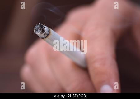 Gros plan de la main d'homme avec la cigarette allumée. Homme fumant de la cigarette Banque D'Images