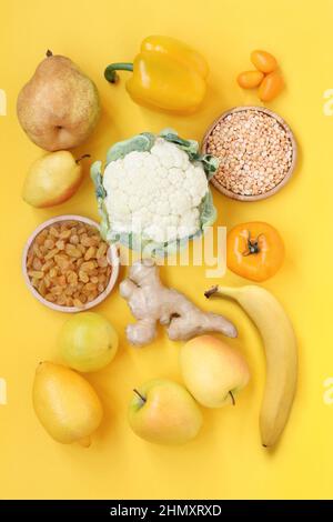 Fruits et légumes jaunes sur fond jaune. Poires, raisins secs, citron, bergamote, pommes, racine de gingembre, paprika, chou-fleur, kumquat, pelée séchée Banque D'Images