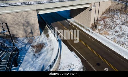 La neige recouvre le trottoir et la rue couverte de glace. Escalier en haut du pont sur le côté. Banque D'Images