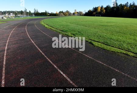 Un vieux, usé et surcultivé avec l'herbe piste de course dans un champ d'école. Banque D'Images