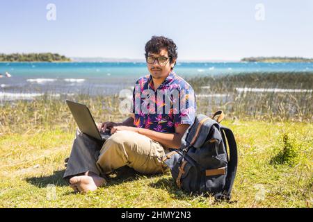 Jeune latino fait du travail en ligne à distance de la plage. Concept de télétravail. Banque D'Images