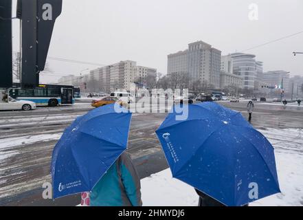 Pékin, Chine. 13th févr. 2022. Les gens attendent de traverser une rue à Beijing, capitale de la Chine, le 13 février 2022. Une chute de neige a frappé Beijing dimanche. Crédit: Lu Peng/Xinhua/Alay Live News Banque D'Images