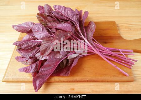 Épinards rouges biologiques frais ou Amaranthus dubius sur planche à découper en bois Banque D'Images