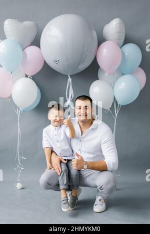 Un père élégant avec son fils de quatre ans sur fond de ballons, célébrant un anniversaire ou la fête de son père Banque D'Images