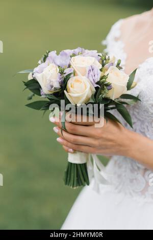 Le bouquet de mariage de la mariée de roses de lait et d'eustoms lilas dans les mains de la mariée Banque D'Images