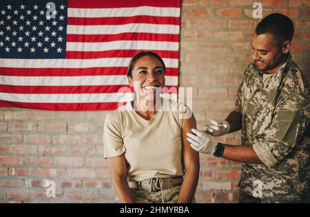 La militaire américaine reçoit une dose du vaccin Covid-19 dans l'hôpital militaire. Une femme joyeuse sourit joyeusement en se faisant entrer Banque D'Images