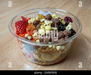 Yaourt grec garni de fruits frais, de noix, de granola et de céréales. Dessert à emporter dans un bol en plastique. Banque D'Images