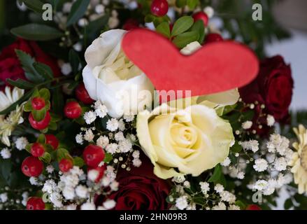 Dortmund, Allemagne. 13th févr. 2022. Un bouquet de roses blanches, gerbera, souffle de bébé et millepertuis avec coeur rouge en bois. Les fleuristes de NRW sont impatients de faire des affaires lundi à la Saint-Valentin. Credit: Bernd Thissen/dpa/Alay Live News Banque D'Images