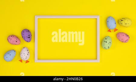 Cadre d'espace de copie blanc avec œufs colorés sur fond jaune. Concept de Pâques Flat Lay Banque D'Images