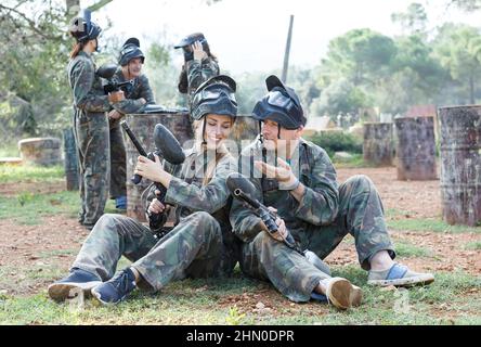 Joueurs de paintball mâles et femelles en camouflage avec masques et pistolets marqueurs Banque D'Images