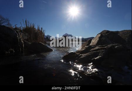 13 février 2022, Bavière, Füssen : la fine couche de glace de l'Hopfensee, située au bord des Alpes, est à l'écoute du soleil. Photo : Karl-Josef Hildenbrand/dpa Banque D'Images