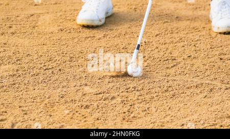 Gros plan d'une personne qui frappe la balle de golf dans un bunker de sable. Entraînement de golf Banque D'Images