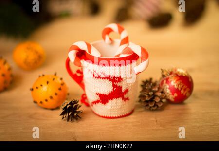 L'abri de la laine en tissu brodé avec mug sur la table en bois de cerf avec mug mandarines et un bonbon Banque D'Images