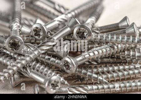 Gros plan des vis argentées universelles avec tête Torx. Vis autotaraudeuses pour bois, contreplaqué ou aggloméré. Les vis Torx se ferment. Banque D'Images