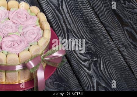 Gâteau avec biscuits Savoiardi et roses guimauves. Attaché avec ruban. Le ruban est attaché dans un noeud. Banque D'Images