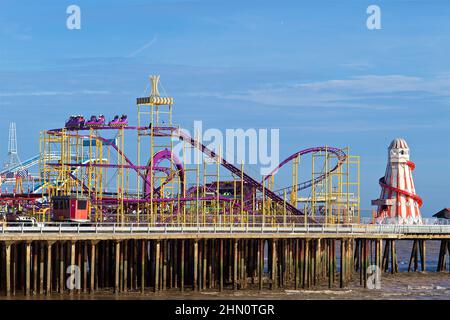 Parc d'attractions Clacton Pier avec montagnes russes et squelette d'hélicoptère, entre autres manèges. Banque D'Images