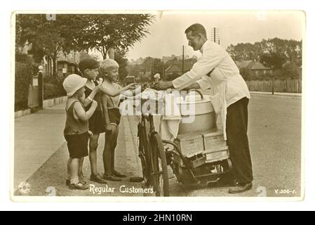 Carte postale originale, archivistique et charmante du début des années 1920, représentant 3 jeunes garçons qui achètent des cônes de crème glacée (cornet cornets), d'un vendeur de crème glacée qui vend des glaces à vélo, dans une rue anglaise suburbaine le jour d'été, des boîtes de wafers de Crawford au dos, vers 1920, au Royaume-Uni Banque D'Images