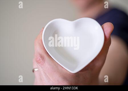 Gros plan d'un homme tenant une soucoupe en forme de cœur. Le concept de l'amour et de la fidélité. Banque D'Images