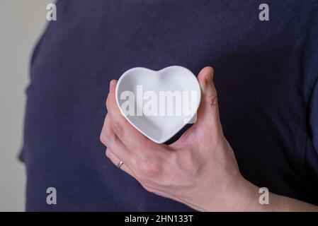 Gros plan d'un homme tenant une soucoupe en forme de cœur. Le concept de l'amour et de la fidélité. Banque D'Images